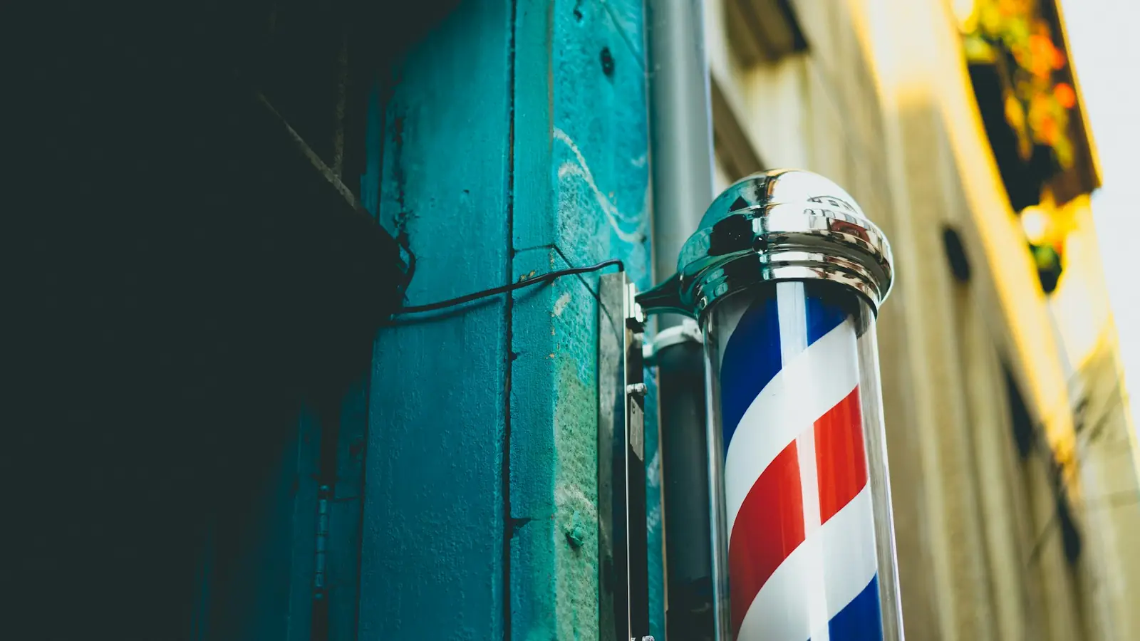 Classic red, white and blue barber pole on a teal wall