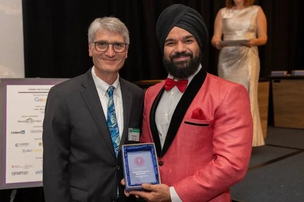 Two men at an awards event holding a framed plaque
