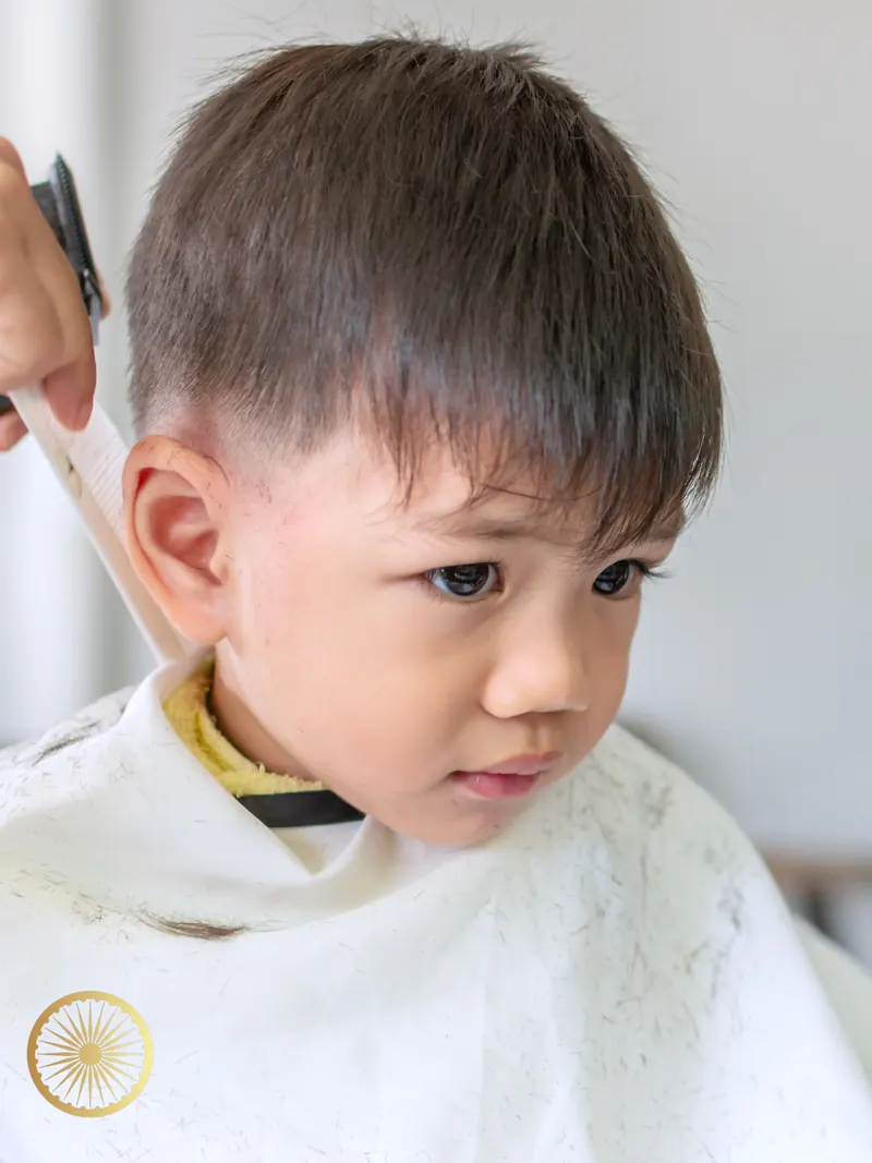 Young boy in a cape with a neat fresh kids' haircut