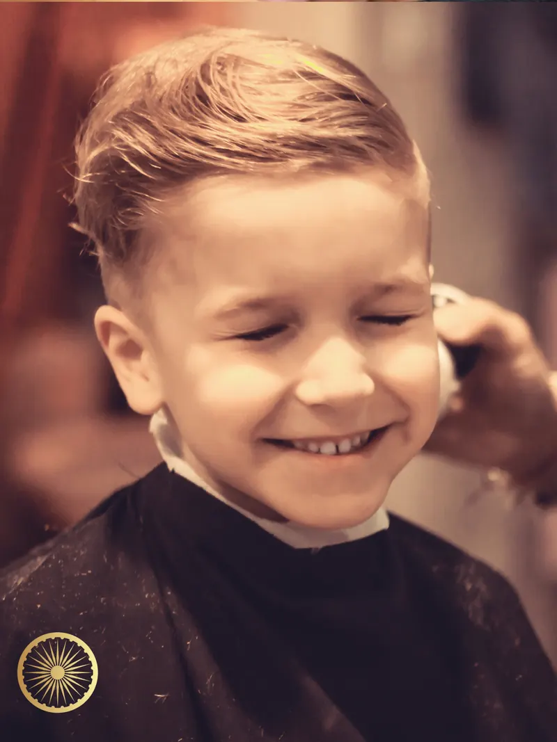 Smiling boy with a fresh side-swept haircut in a barber cape